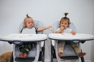 Twins in high chairs sharing their lunch
