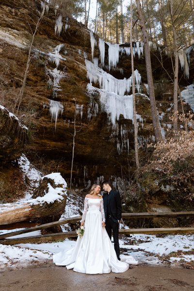 Couple looking at each other in front of a cliff with icicles at Hocking Hills State Park in Ohio.