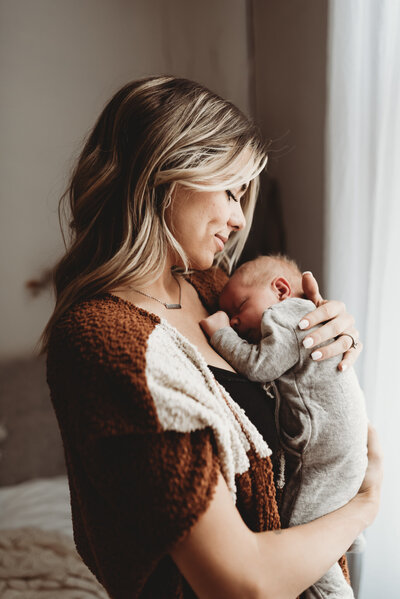Taking in each fleeting moment, a momma embraces her newborn baby boy during a studio session at Nikii Pix.