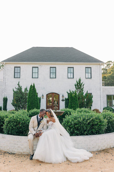 Couple in front of white brick wedding venue on wedding day