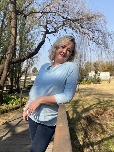 Yvette Pretorius is standing on a bridge, smiling to welcome new clients
