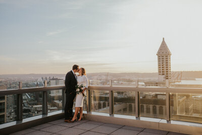 Bride and Groom kissing on top of a city building at sunset