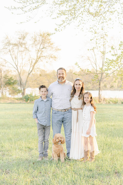 family posing for photo with their dog during a sunny day in Haymarket, VA spring mini session