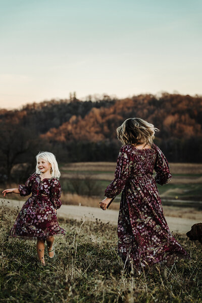Mother and daughter twirling on Wisconsin hillside in fall.