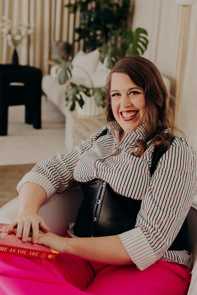 woman in striped shirt and corset sitting in a chair and smiling