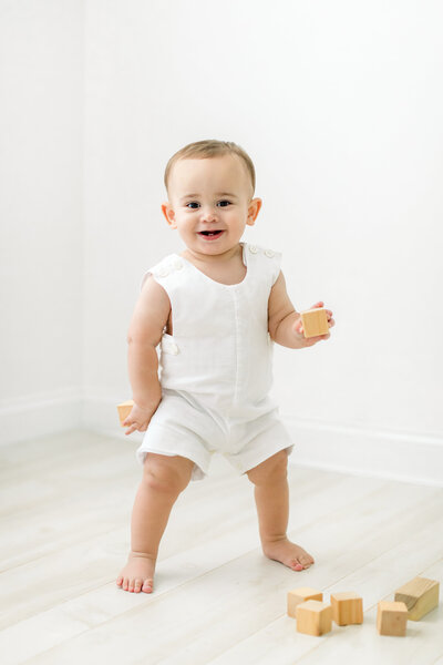 photo of little boy in jon jon standing and playing with blocks