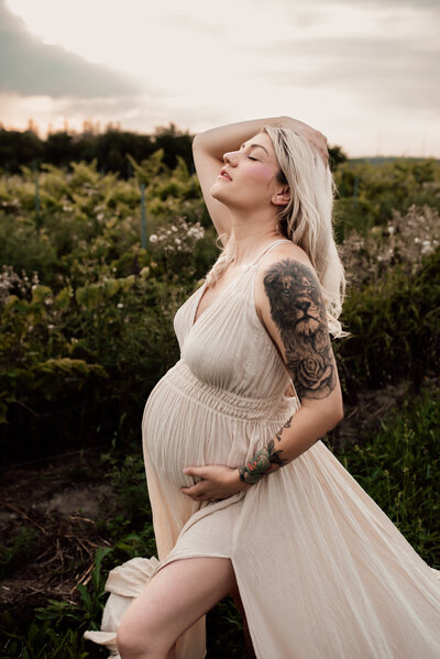 Pregnant mother in a long linen dress in front of a vineyard