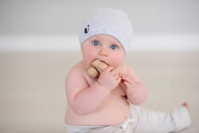 Baby boy chewing on a wooden toy in Boise photo studio.