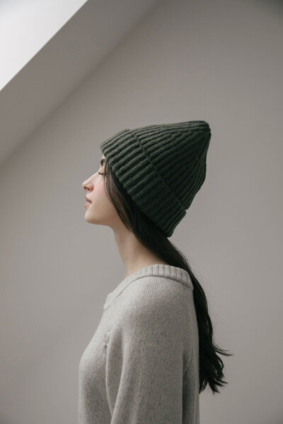 Girl gazing out the window in green tuck and oat sweater