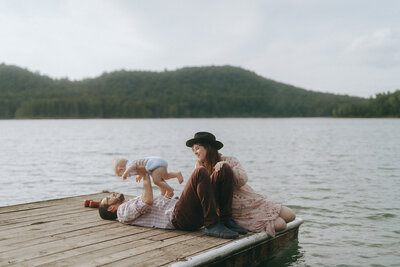 couple lying on dock holding baby during newborn photography session by Elsie Goodman 