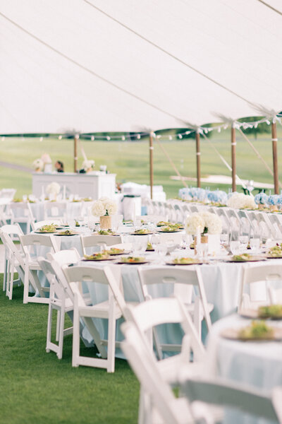 White tables of wedding reception under sailcloth tent in Virginia