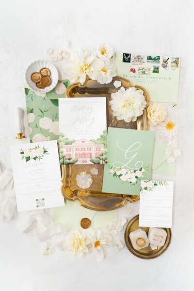 Sophisticated sage green custom  wedding invitations with white floral details, including an RSVP card, details card, and envelope with calligraphy