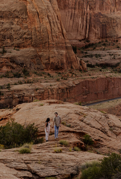 Couple Hiking and Holding Hands for their engagement photos In the Moab Desert in Utah