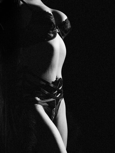 A stunning woman in laying upside down on a bed in lingerie.