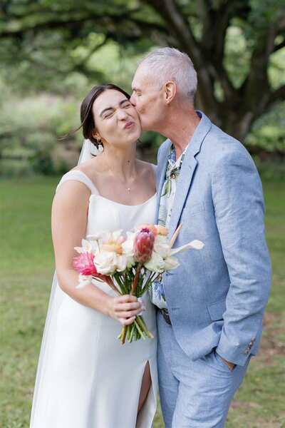 A parent kissing their child's cheek on their wedding day 