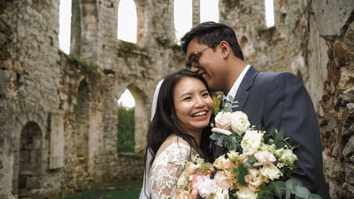 bride and groom laughing destination wedding at French castle with bouquet