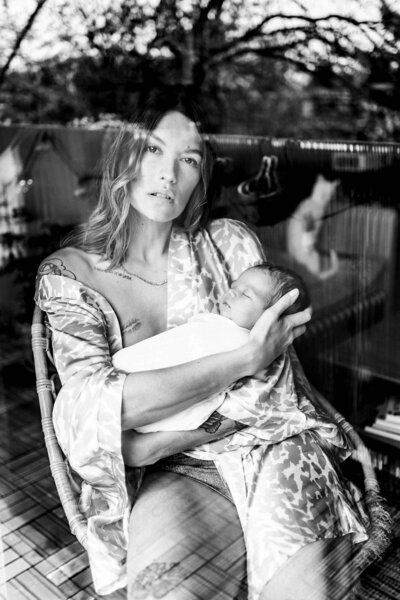 photo noir et blanc d'une femme avec un bébé dans les bras à travers une vitre