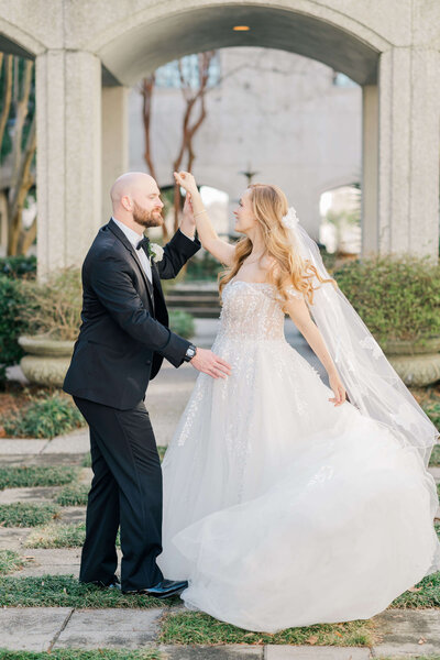 Groom dancing and twirling bride with brides dress flowing