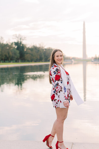 A graduate walks in front of the National Monument in DC during her sunrise senior photo session