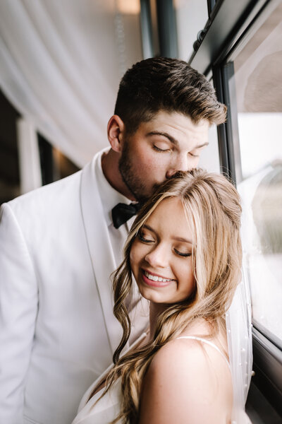 A groom kissing his wifes head at their wedding