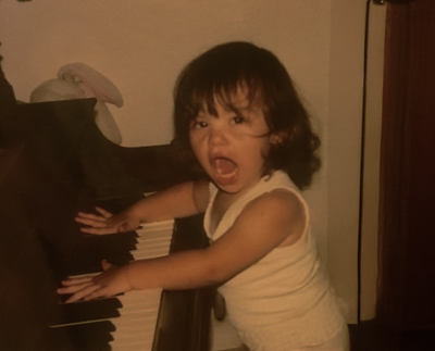 Childhood photo of Dempsey playing the piano, showcasing his early passion for music and creativity, which later influenced his approach to nurturing children's development at Brave Nature School.