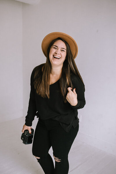 Kaitlin Powell Photography laughing and holding her camera. 