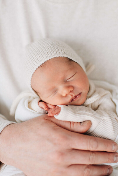 newborn in dad's hands on his chest