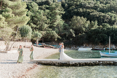 Bridal party stepping off a boat to walk up the aisle at a romantic Ionian Islands wedding, planned with refined coastal elegance.