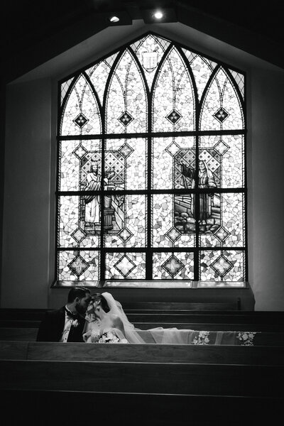 A newly married couple kisses in the light of a stained glass window in a North Georgia chapel. 