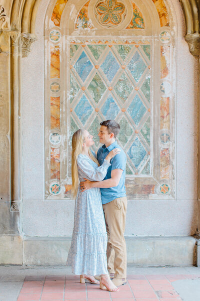Engagement photo of couple standing in front of an ornate wall
