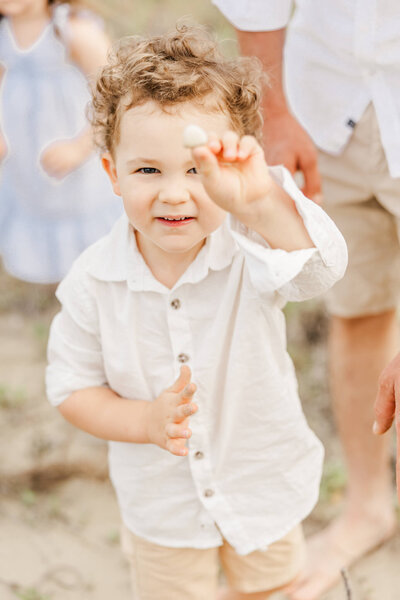 A little boy holding up a sea shell at the beach near Yeppoon. 
