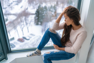 Woman looking sad staring out window