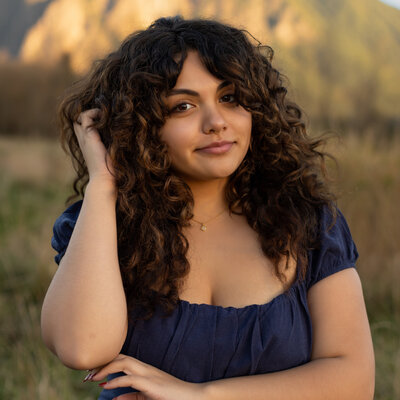 beautiful girl with natural curly brown hair laughing in field in Snoqualmie Washington with Mount Si in the backdrop