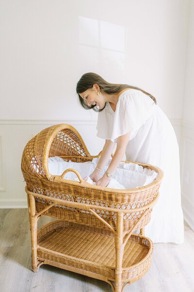 mom reaching into bassinet for baby