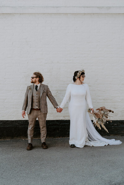 An alternative bride in a disco ball dress and her groom in a custom tweed suit on their wedding day. 