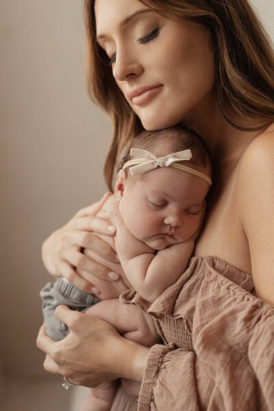Mother holding newborn close captured by a Michigan photographer