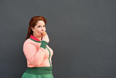 Wedding planner wearing a watermelon cardigan and eating ice cream outside