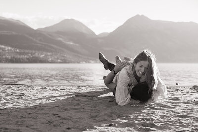 Couple embracing and laughing during their engagement session on the beach in Colorado — capturing genuine love and emotion in a relaxed, documentary style