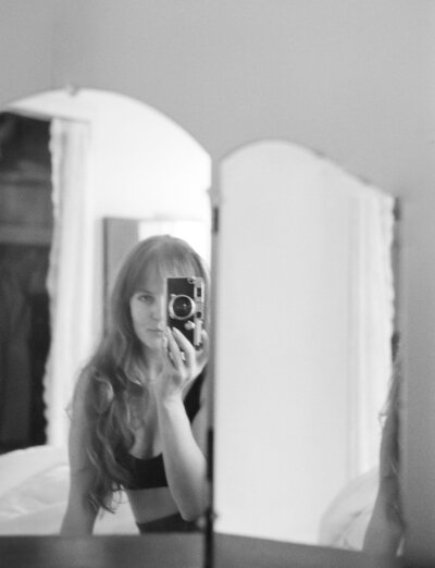 artistic photographer mirror self portrait with vintage rangefinder camera, vanity mirror, female photographer