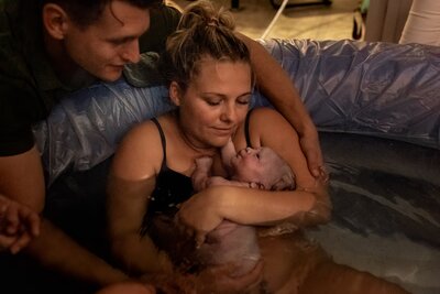 Pasgeboren baby na een badbevalling, vastgelegd door een geboortefotograaf.