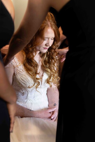Bride holding wedding bouquet while smiling down at the flowers
