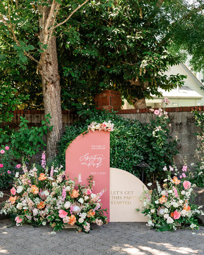 Flowers and wedding day signage welcome guests with customized calligraphy by Life in Letters.