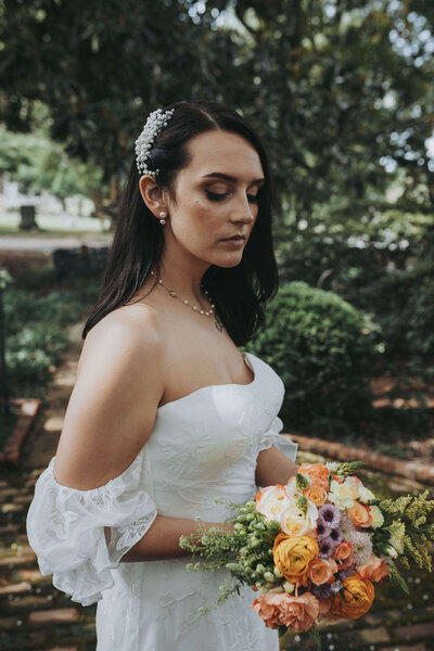 Portrait of a bride looking at her handmade bouquet at Elmwood Cemetery