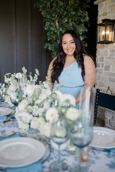 Bridesmaid in blue dress sitting at floral wedding table