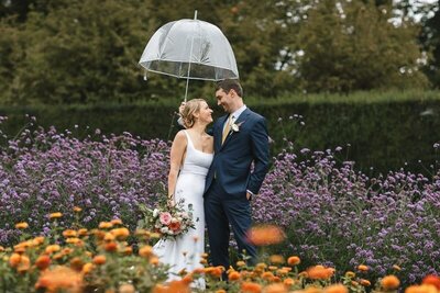 Couple  smiling at each while standing in a garden while raining in Seattle.