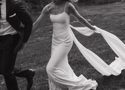black and white photo of bride and groom running