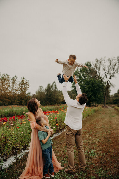 Mother and father playfully holding their two kids up in the air.