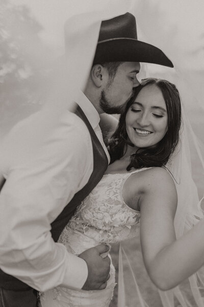 Groom kissing bride under veil during their fall Minnesota Wedding.