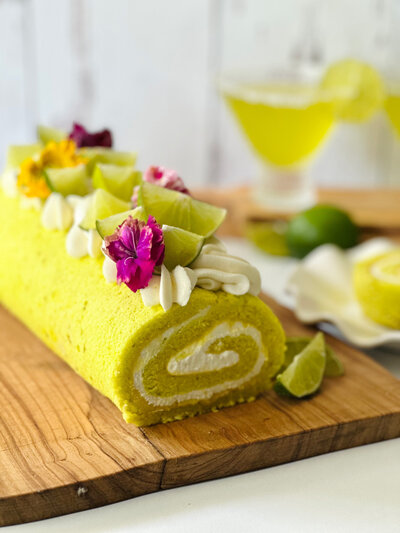 lime swiss roll cake with white filling decorated with fresh limes and flowers