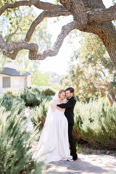 Gay couple embraces in laughter in tuxedos on their wedding day